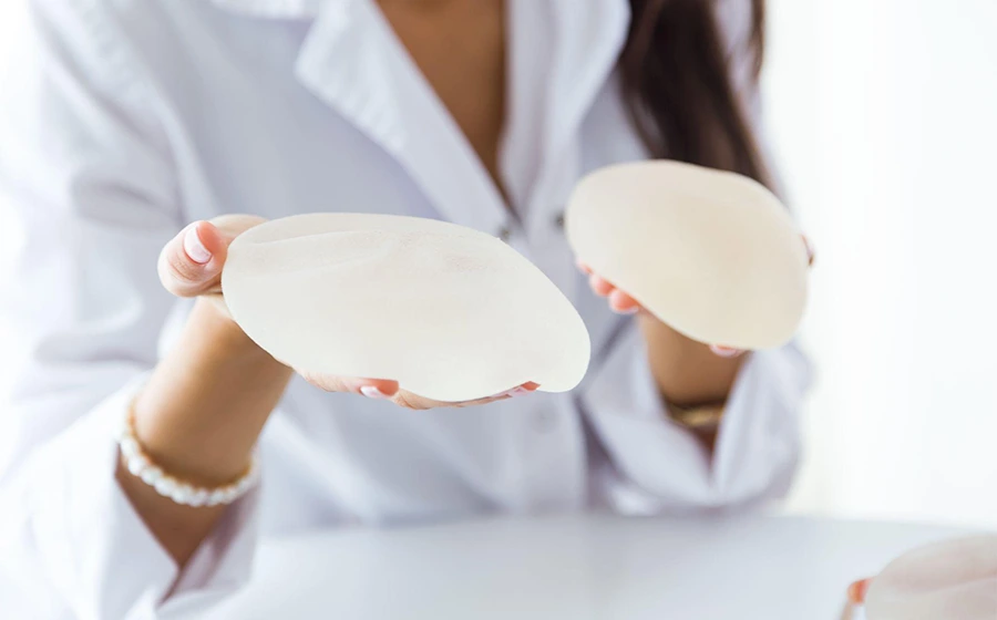 A female doctor holding silicone breast implants, demonstrating options for breast augmentation surgery in Bangalore.