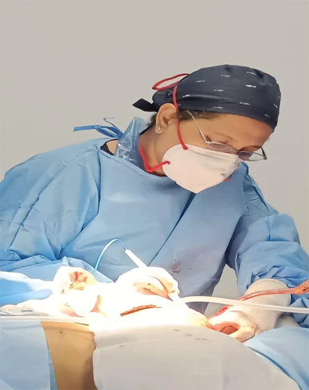 Surgeon in surgical attire performing a liposuction procedure in an operating room, demonstrating expert care at Pink Apple Aesthetics in Bangalore