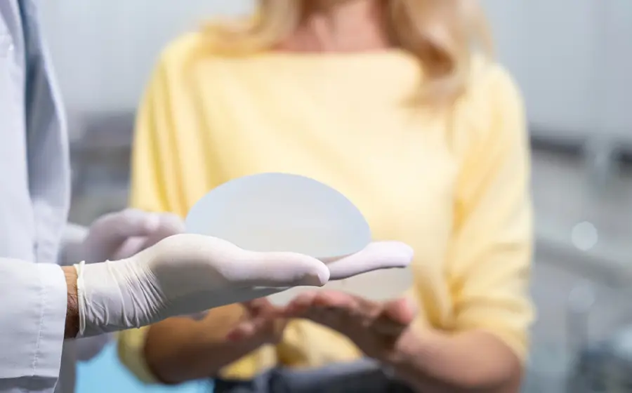 Plastic surgeon showing a breast implant to a patient during consultation about breast augmentation.