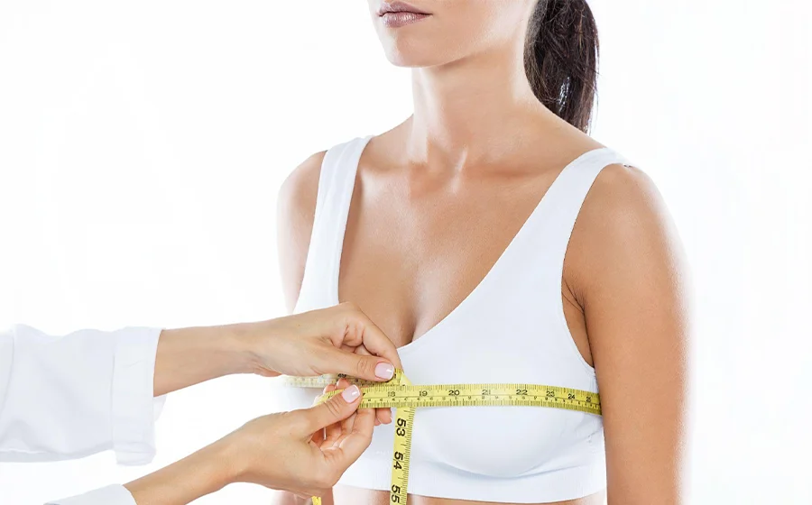 Doctor measuring woman's chest after breast fat transfer to check for lumps or fat necrosis