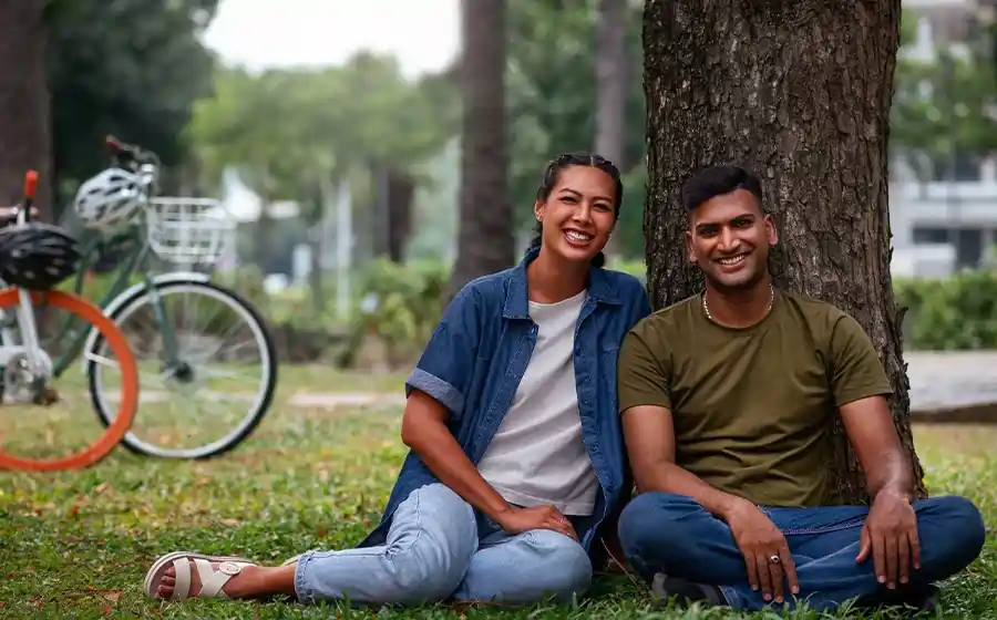 A happy couple sitting and relaxing under a tree in a Bangalore park