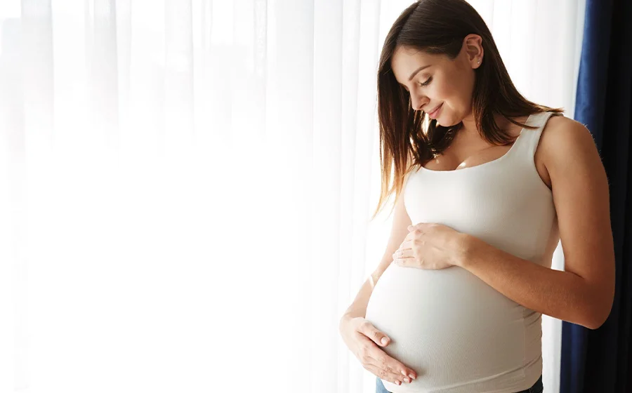 Pregnant woman holding belly after tummy tuck surgery in Bangalore
