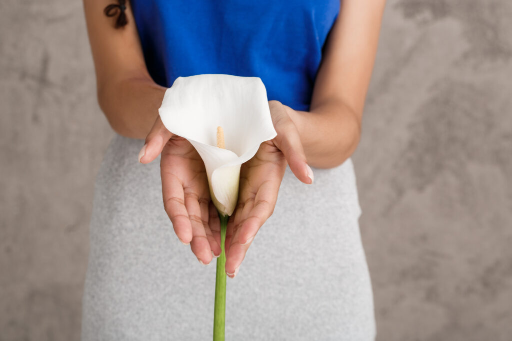 pretty young woman holding white flower beige wall