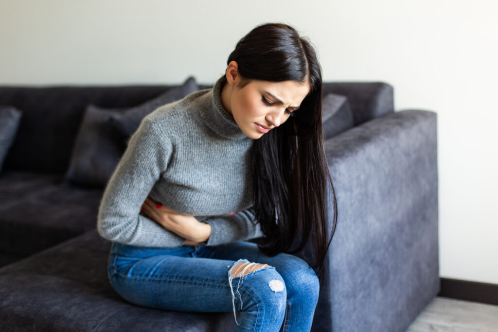 sick woman having stomachache living room