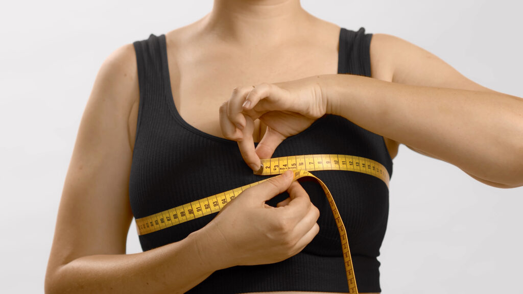 white unrecognizable anonymous lady black top measures her bust with tape bra fitting studio no head shot high quality photo image white background 3 1
