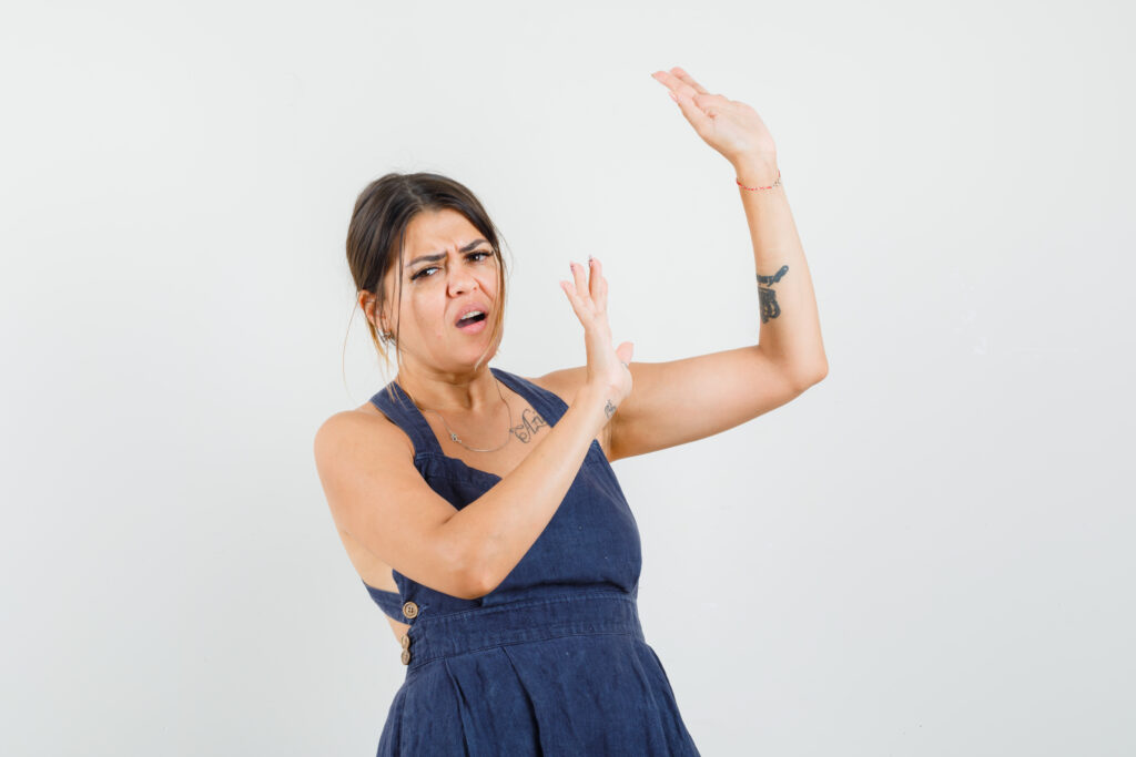 young woman raising hands preventive manner dress looking worried